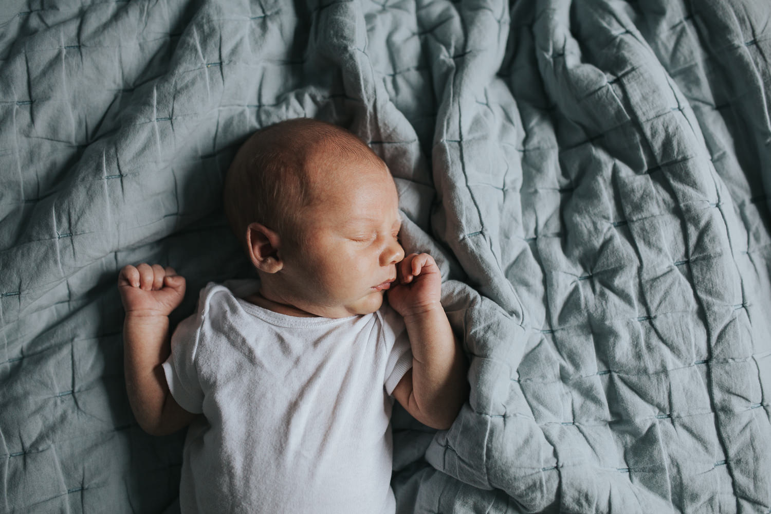 2 week old baby boy lying on bed asleep with hands near face - Barrie Lifestyle Photos