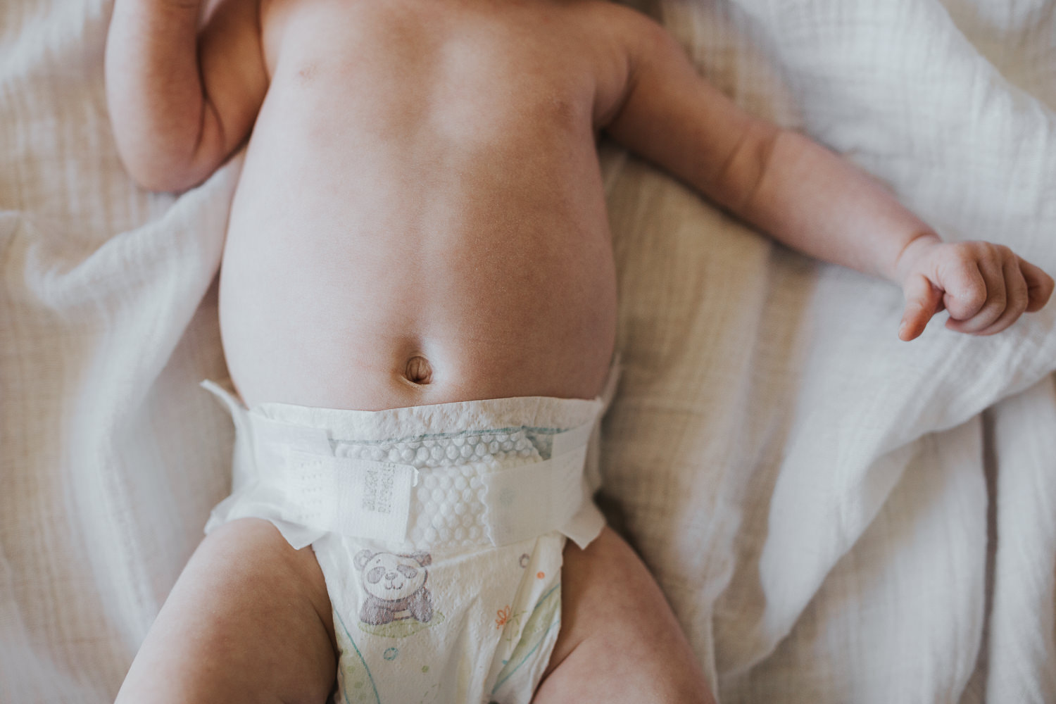 2 month old baby girl in diaper lying on white swaddle, close up of belly button - Uxbridge Lifestyle Photos