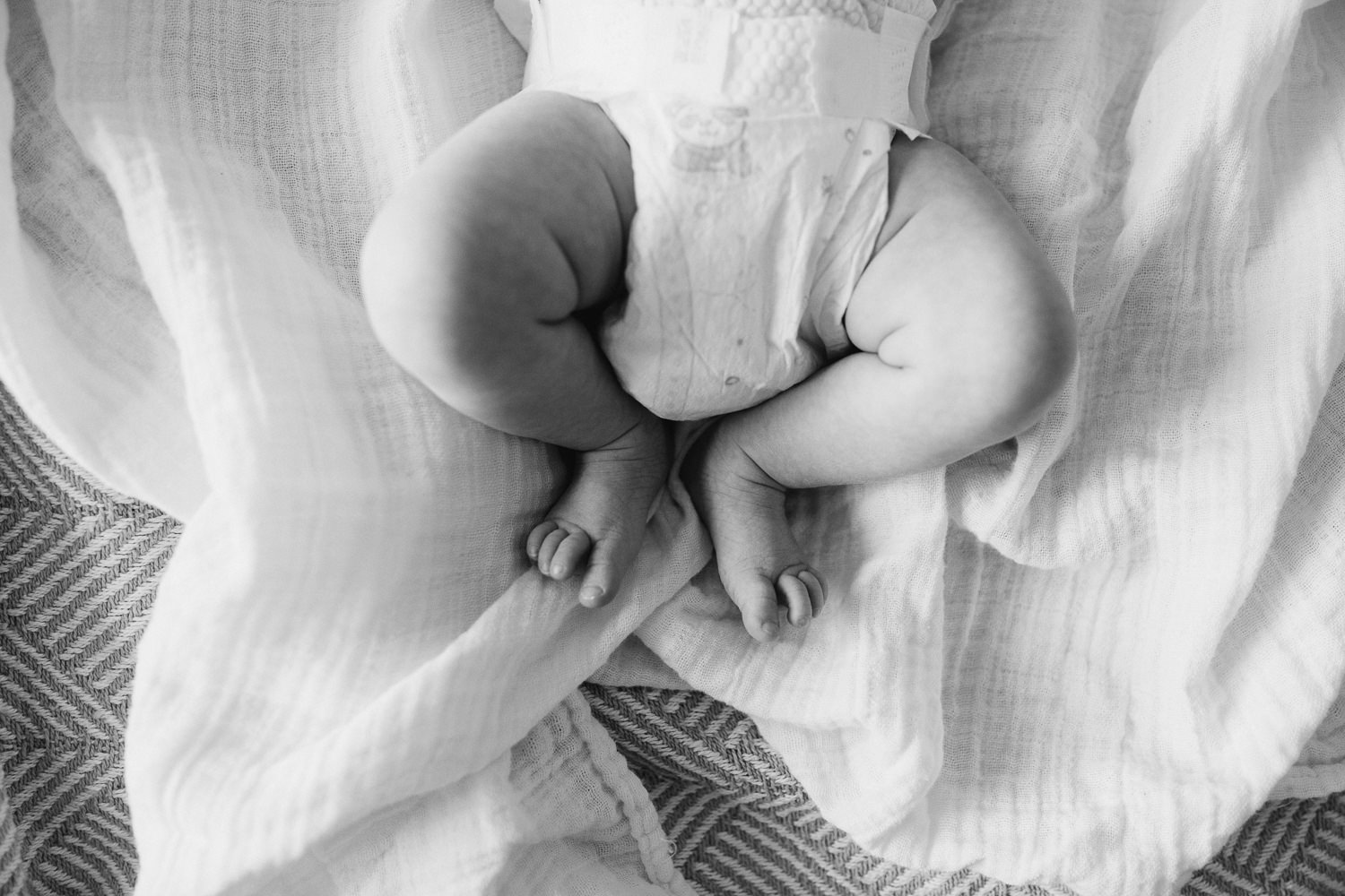 2 month old baby girl in diaper lying on white swaddle, close up of feet - Newmarket In-Home Photos