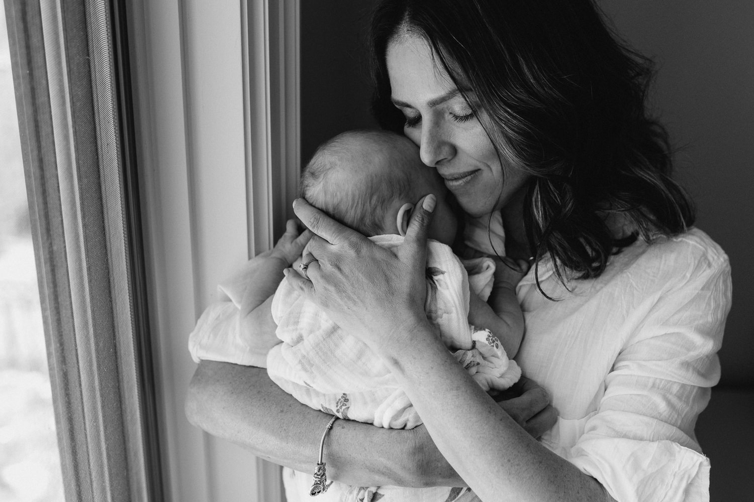 first time mother with eyes close snuggling 2 month old baby girl to chest - Barrie Lifestyle Photography