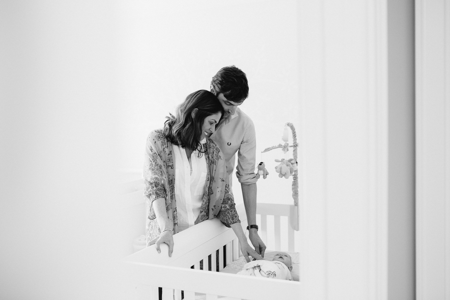 husband and wife stand in nursery looking into crib at 2 month old baby girl - Stouffville Lifestyle Photos