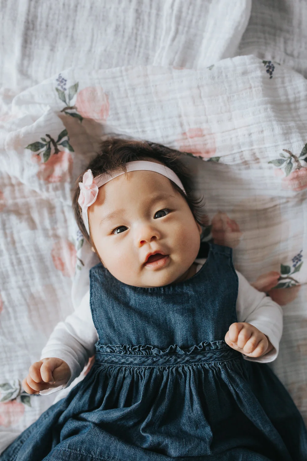 3 month old baby girl in blue dress lying on floral blanket looking at camera - Stouffville Lifestyle Photography