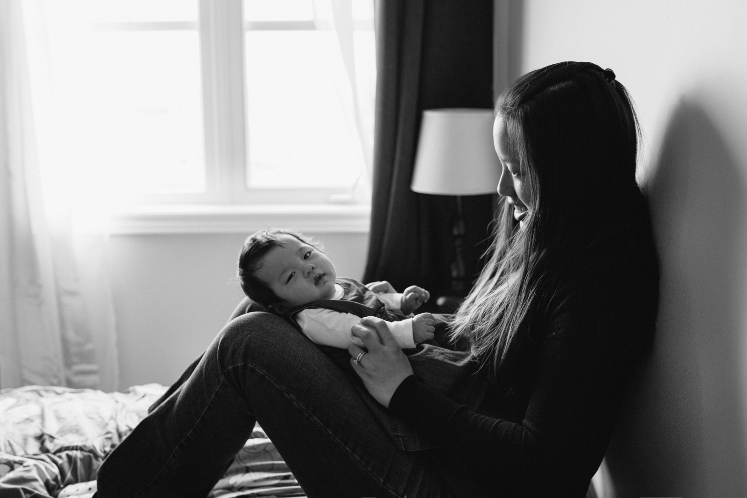 3 month old baby girl lying on mom's legs on master bed, mother looking at daughter - Markham Lifestyle Photos