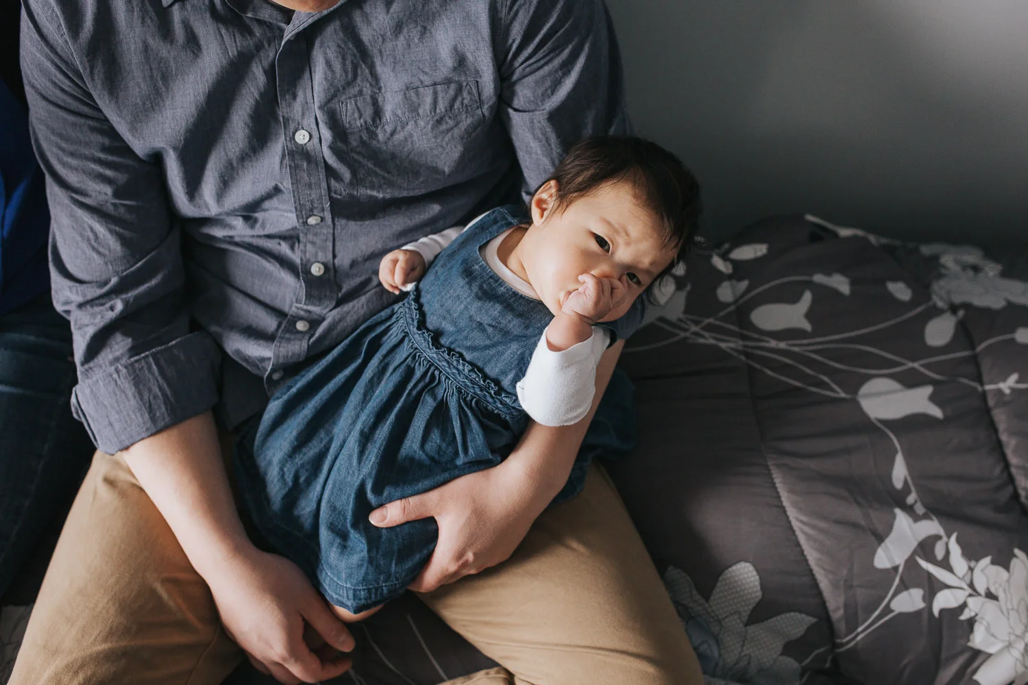 3 month old baby girl in father's arms sucking thumb and looking at camera - Newmarket In-Home Photos