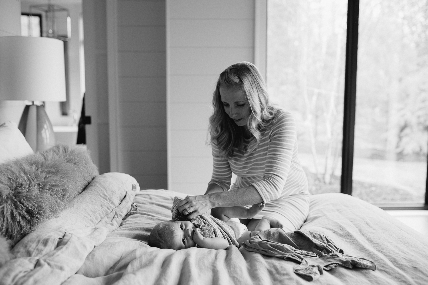 mom changing 6 month old baby girl's outfit on bed - Markham Lifestyle Family Photos