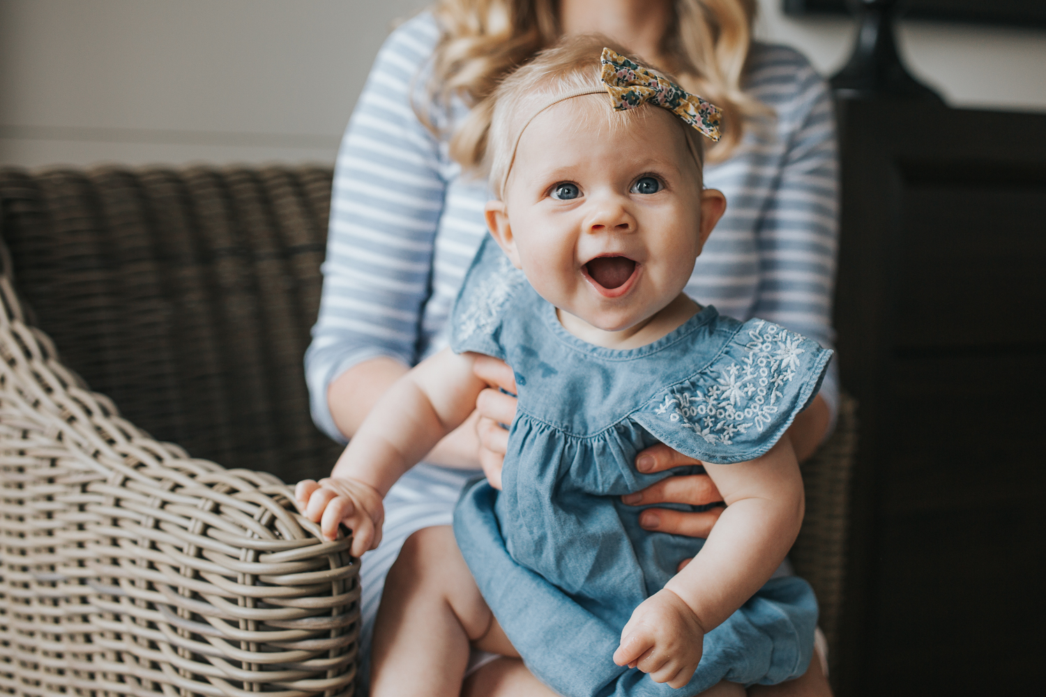 6 month old baby girl in blue dress sitting on mom's lap laughing - Barrie Lifestyle Family Photos