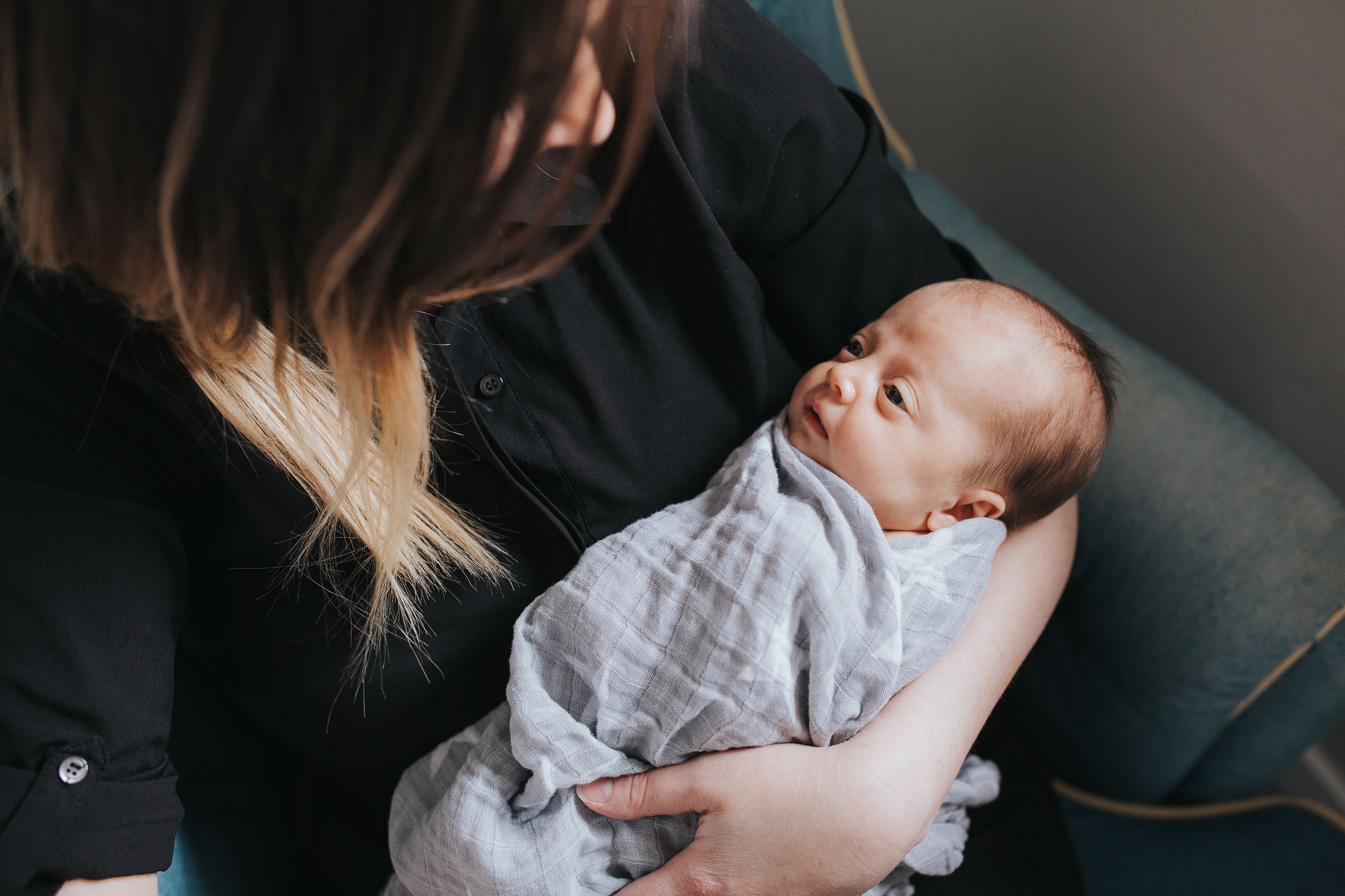 first time mom sits in chair holding at baby girl - Stouffville Lifestyle Photography