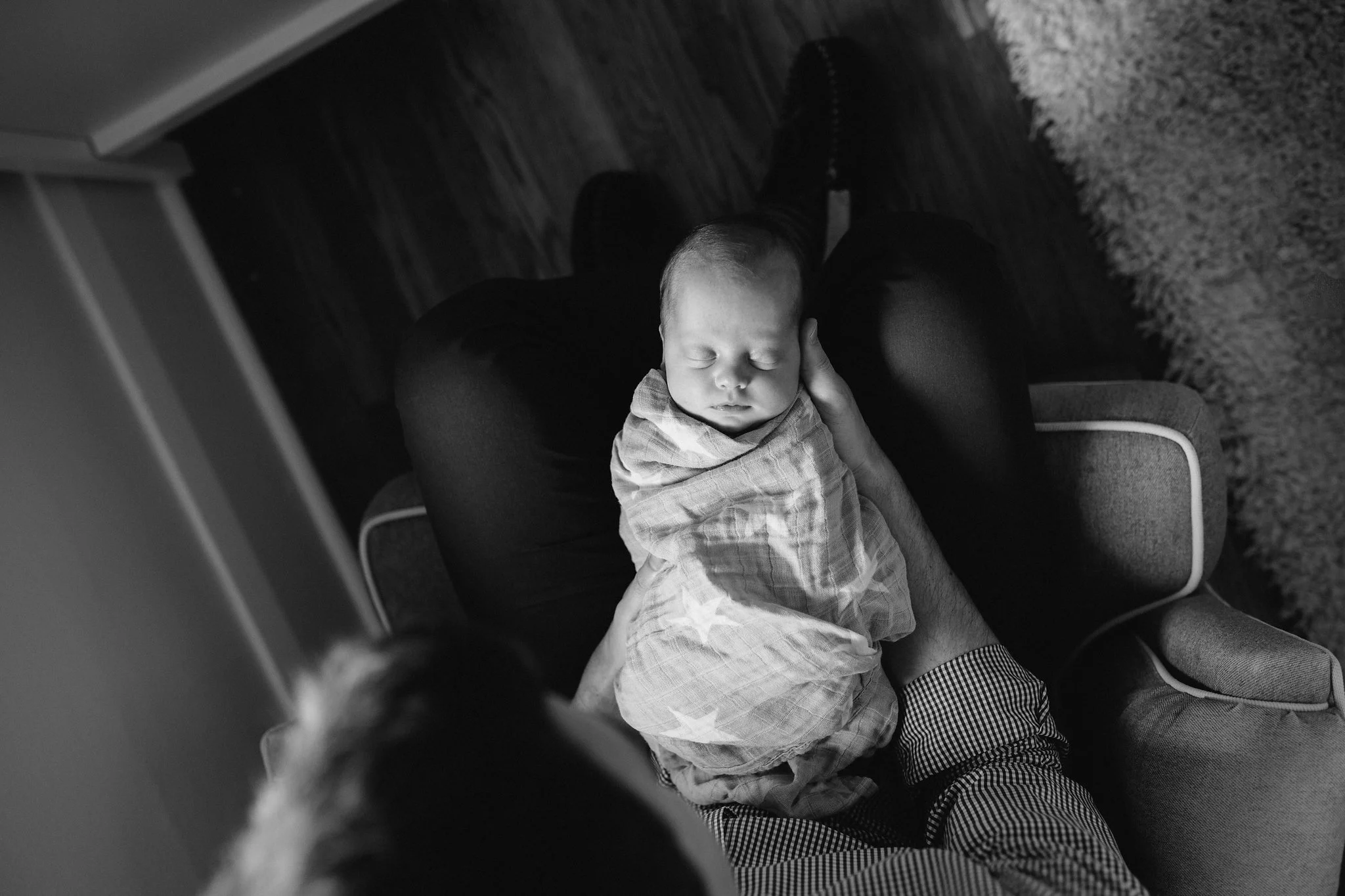 shot from above of baby girl in grey swaddle lying in her father's lap - Barrie Lifestyle Photography