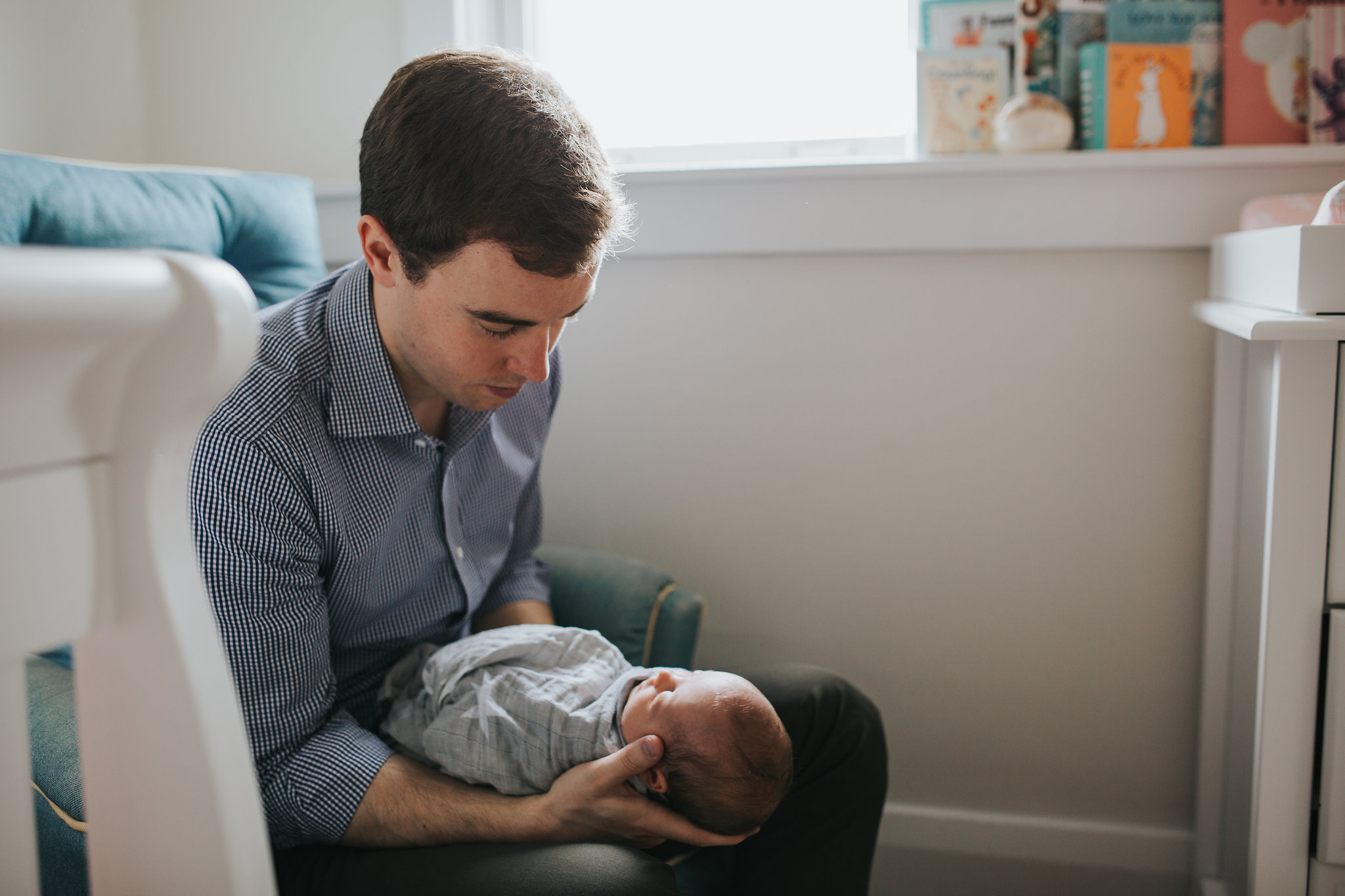 new dad sitting in chair holding and looking at baby daughter - Newmarket In-Home Photography