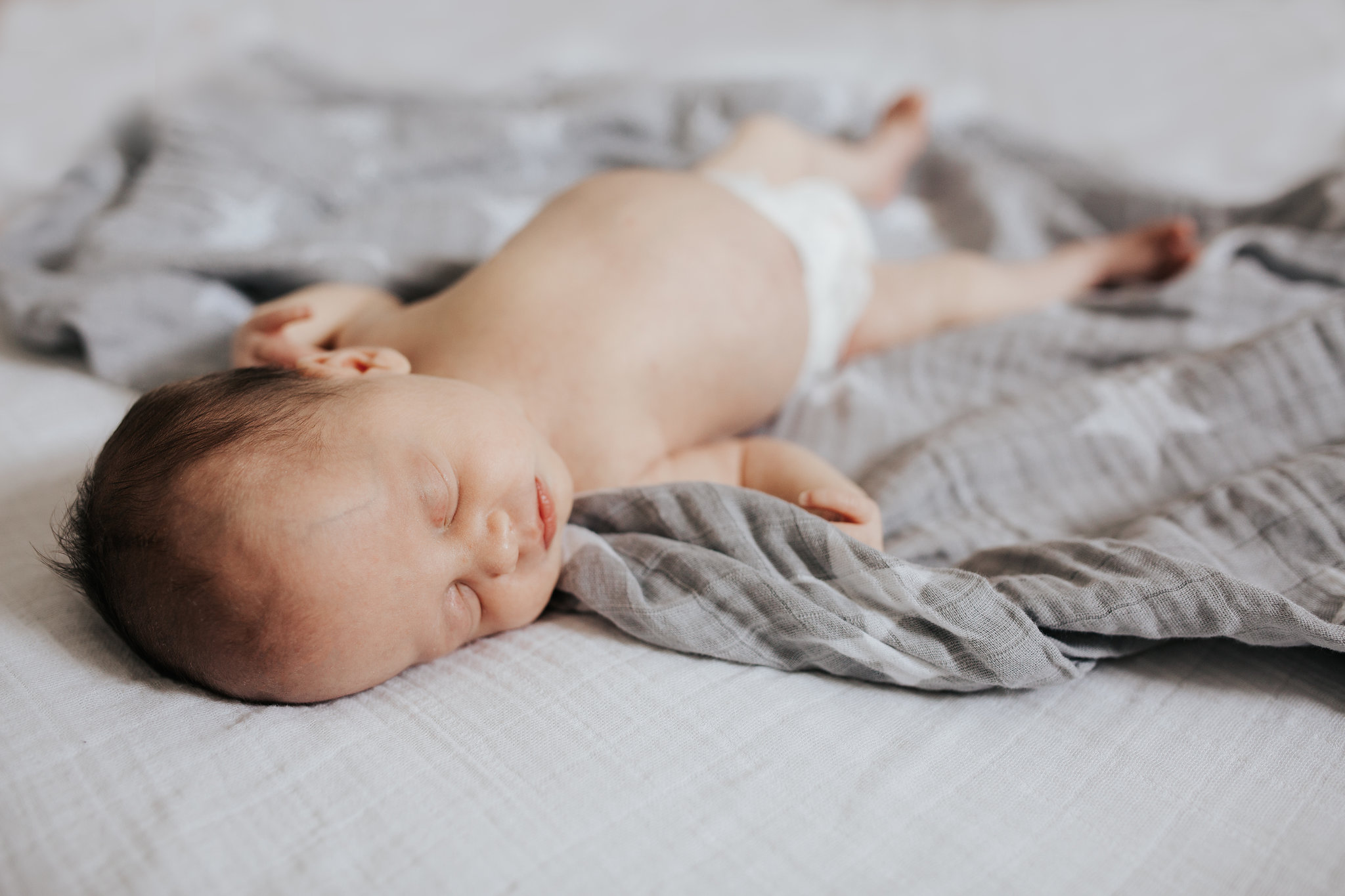 4 week old baby girl asleep in diaper lying on swaddle - Newmarket In-Home Photos