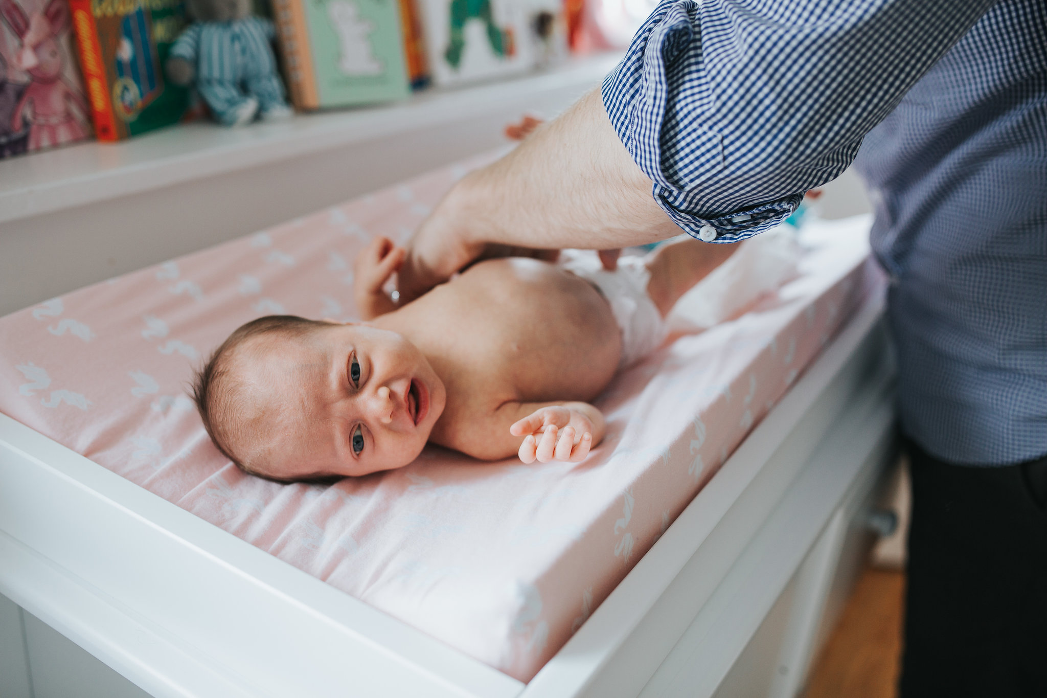 4 week old baby girl lying on change table as dad changes diaper - Stouffville In-Home Photos