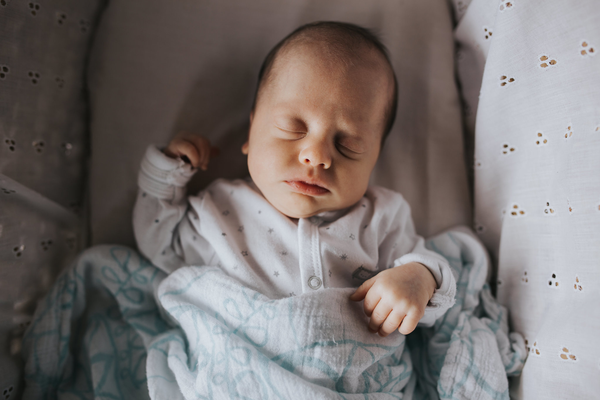 4 week old baby girl sleeping in Moses basket wearing a sleeper and covered in swaddle - Newmarket In-Home Photos