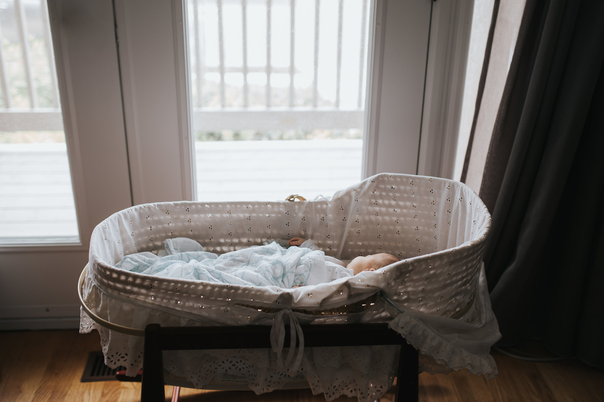 4 week old baby girl sleeping in Moses basket wearing a sleeper and covered in swaddle - Stouffville In-Home Photos