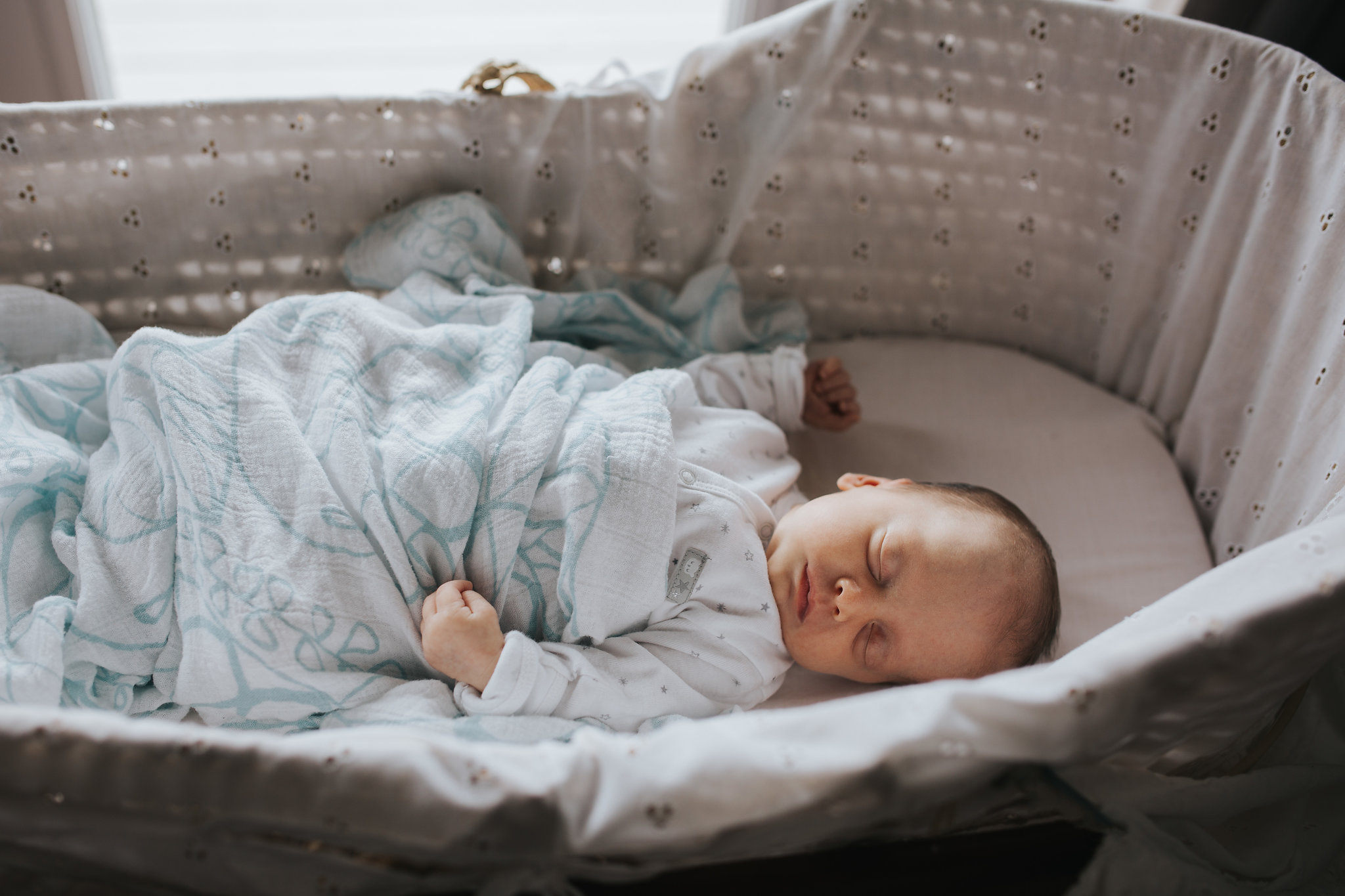 4 week old baby girl sleeping in Moses basket wearing a sleeper and covered in swaddle - Barrie In-Home Photos