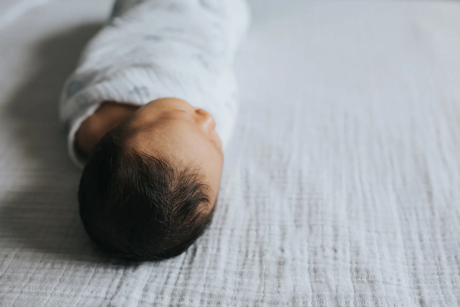 2 week old baby boy lying on bed in blue and white swaddle - Markham Lifestyle Photography