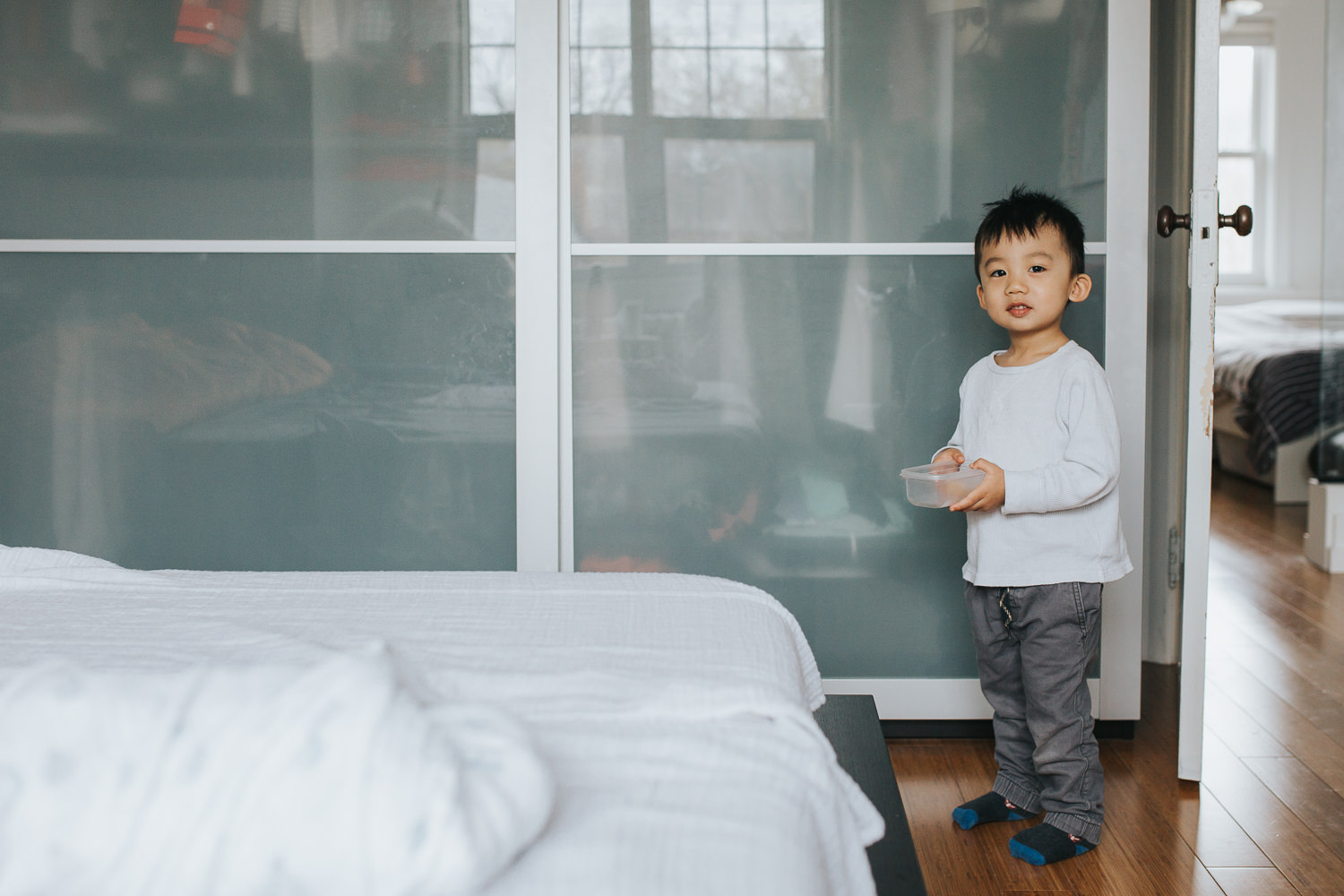 2 year old toddler boy standing with snack in hand, looking at camera - Markham In-Home Photography