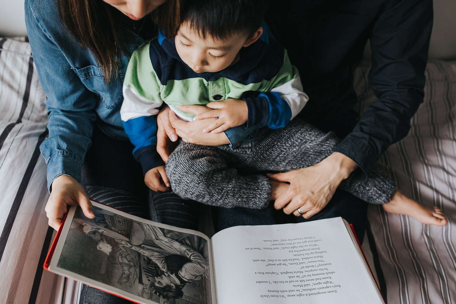 mom and dad sitting on bed reading story to 2 year old toddler son - Barrie Lifestyle Photos