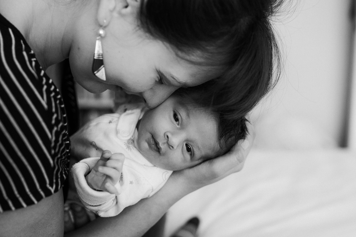 first time mom snuggling 2 week old baby daughter, face to face, baby looking at camera - Newmarket Lifestyle Photography