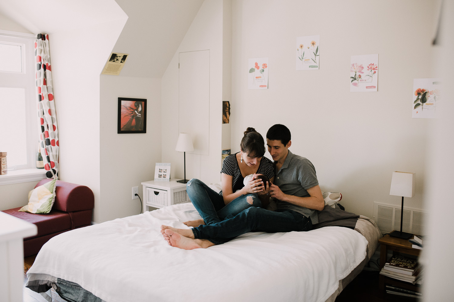 family of 3 sitting on bed, parents looking at 2 week old baby girl - Stoufffville Lifestyle Photography