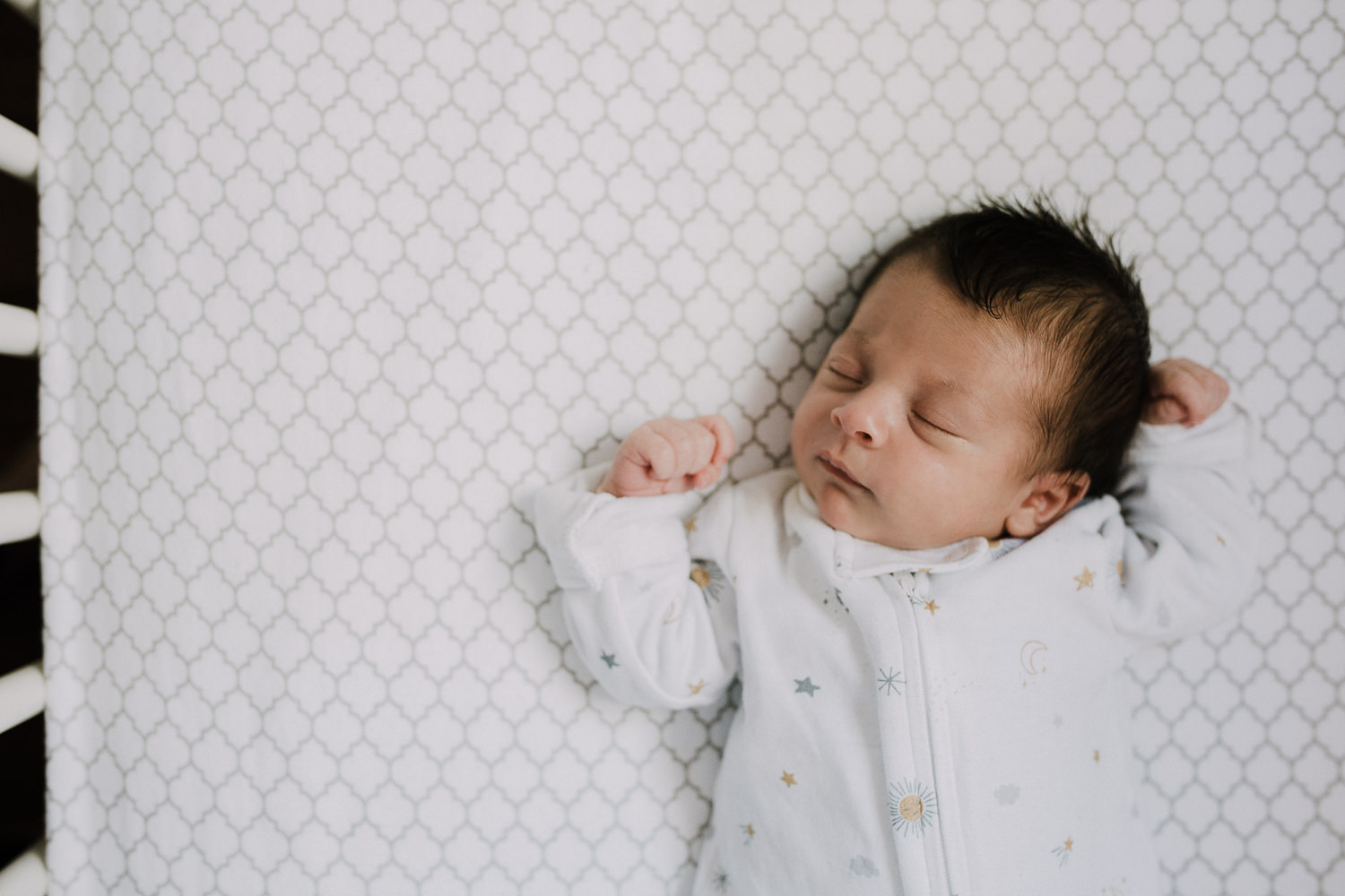 2 week old baby girl in white sleeper lying asleep in crib - Barrie Lifestyle Photography