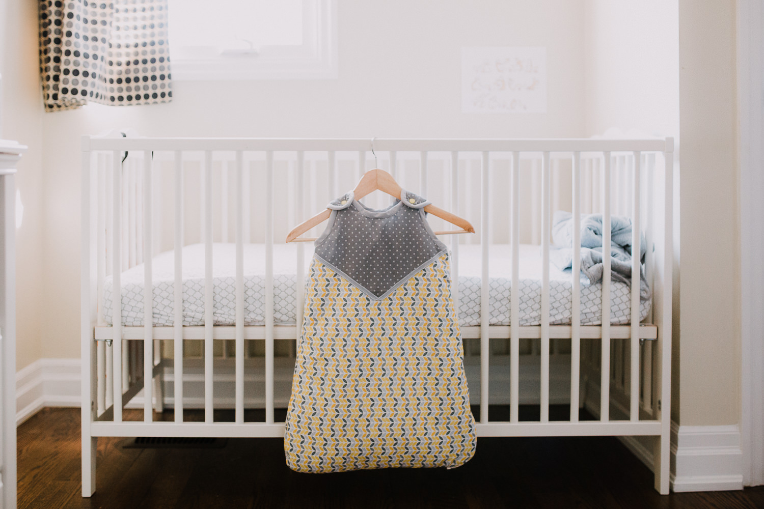 handmade yellow and grey sleep sack hanging on crib in nursery - Markham Lifestyle Photography