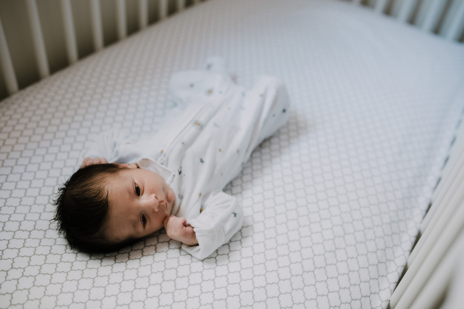 2 week old baby girl in white sleeper lying in crib - Stouffville In-Home Photography