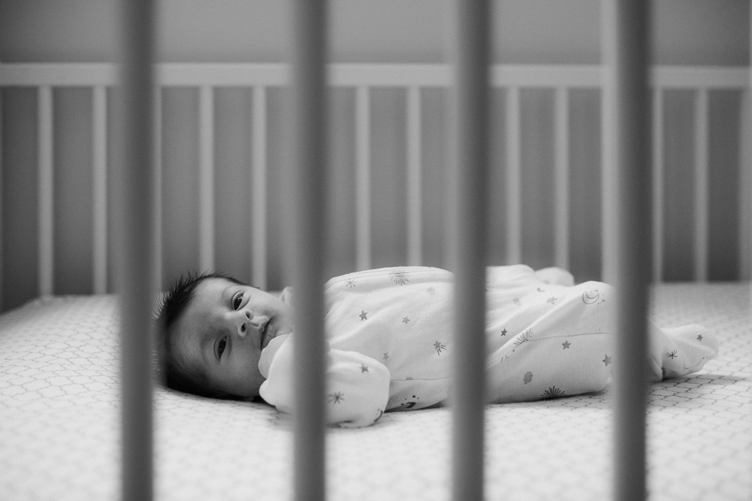 2 week old baby girl in white sleeper lying in crib - Newmarket In-Home Photos