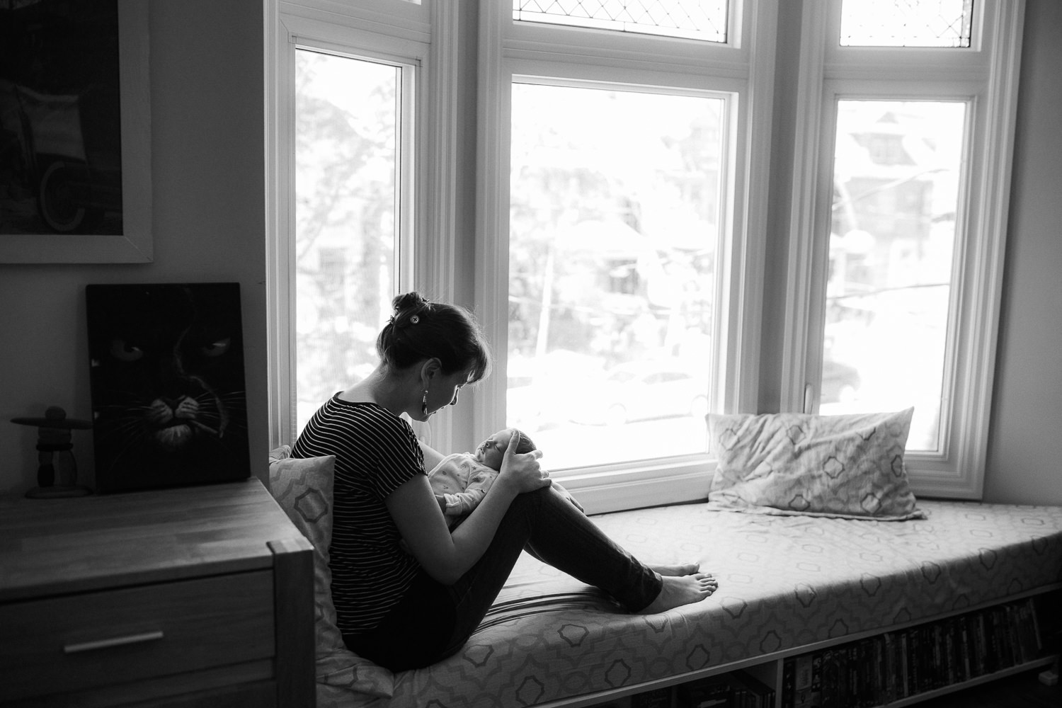 new mom sitting on window seat holding 2 week old baby girl - Newmarket Lifestyle Photography