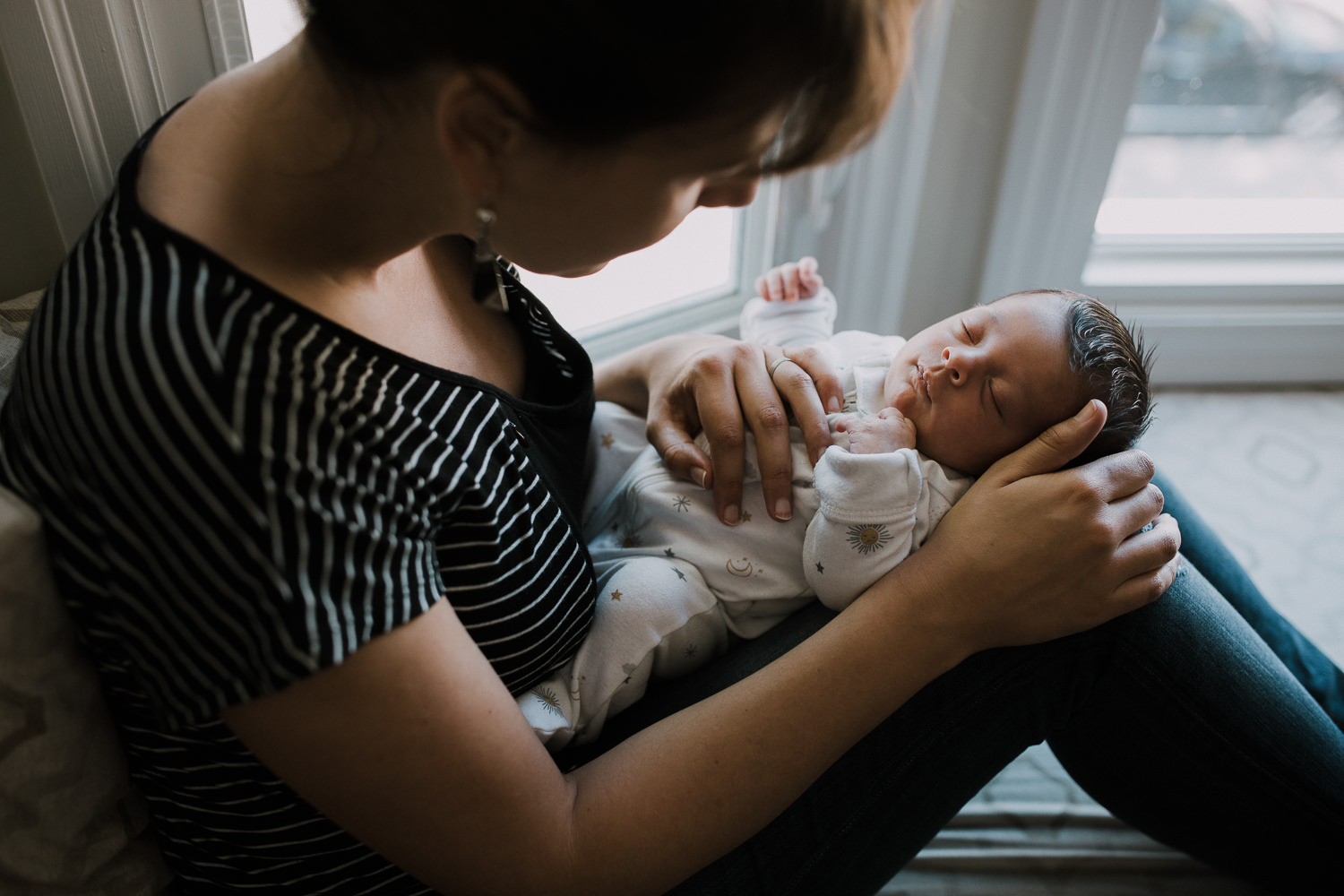 new mom sitting on window seat holding 2 week old baby girl - Stouffville Lifestyle Photography