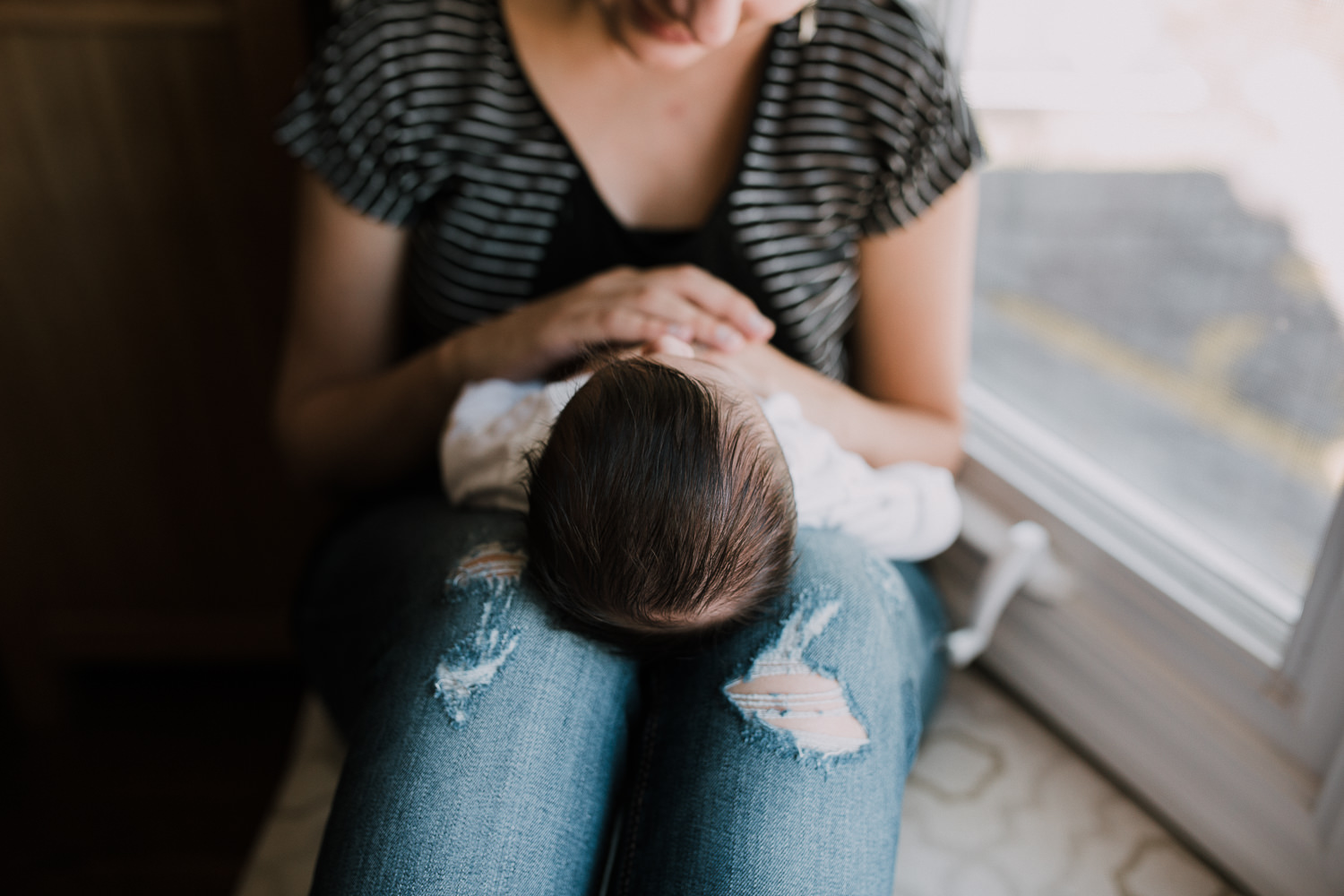 new mom sitting on window seat holding 2 week old baby girl, close up of hair - Markham Lifestyle Photography