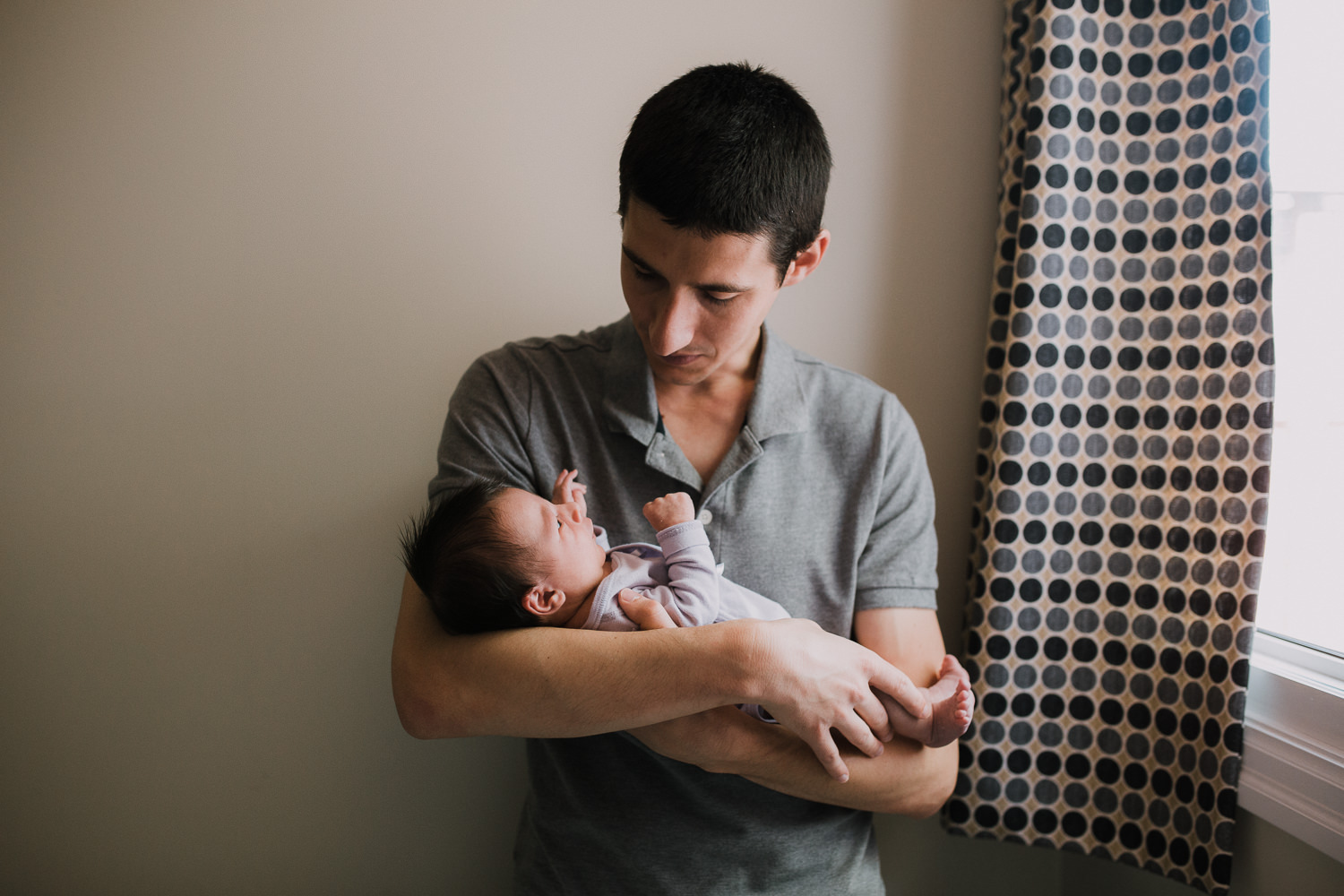 first time dad holding and looking at 2 week old baby girl - Barrie In-Home Photography