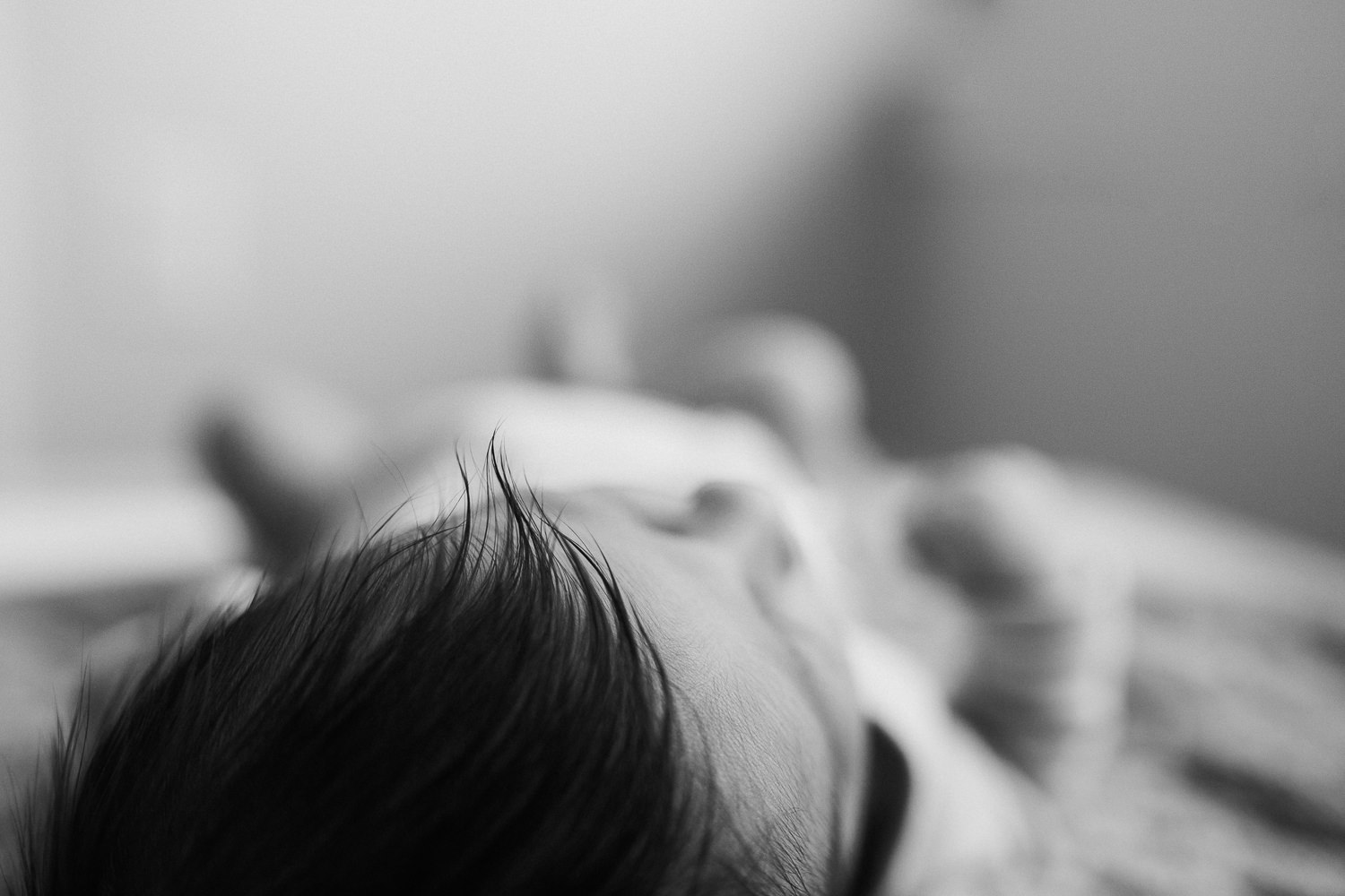 2 week old baby girl lying on bed, close up of dark wisp of hair - Markham In-Home Photos