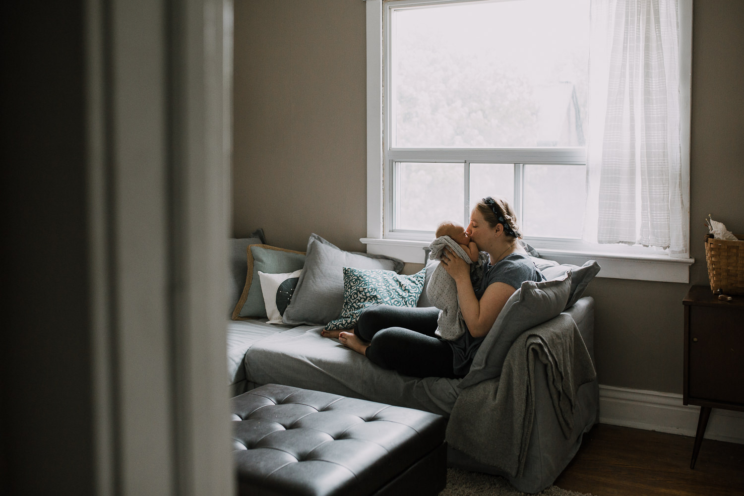 mom sits on couch with 10 day old baby boy, kissing his face - Markham In-Home Family Photos