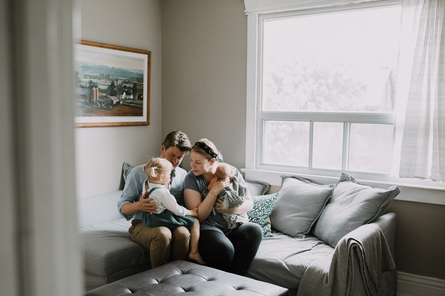 family of four with 2 year old toddler girl and 10 day old baby boy sitting on couch together - Stouffville Lifestyle Family Photos