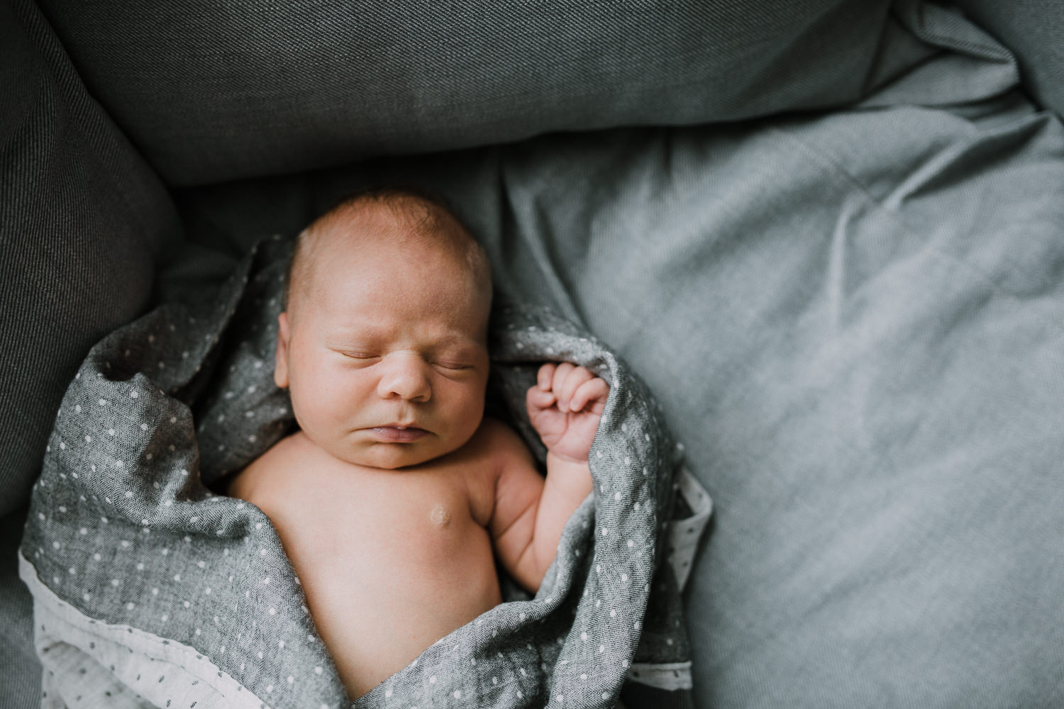 10 day old baby boy in loose swaddle asleep on couch - Barrie Lifestyle Family Photography