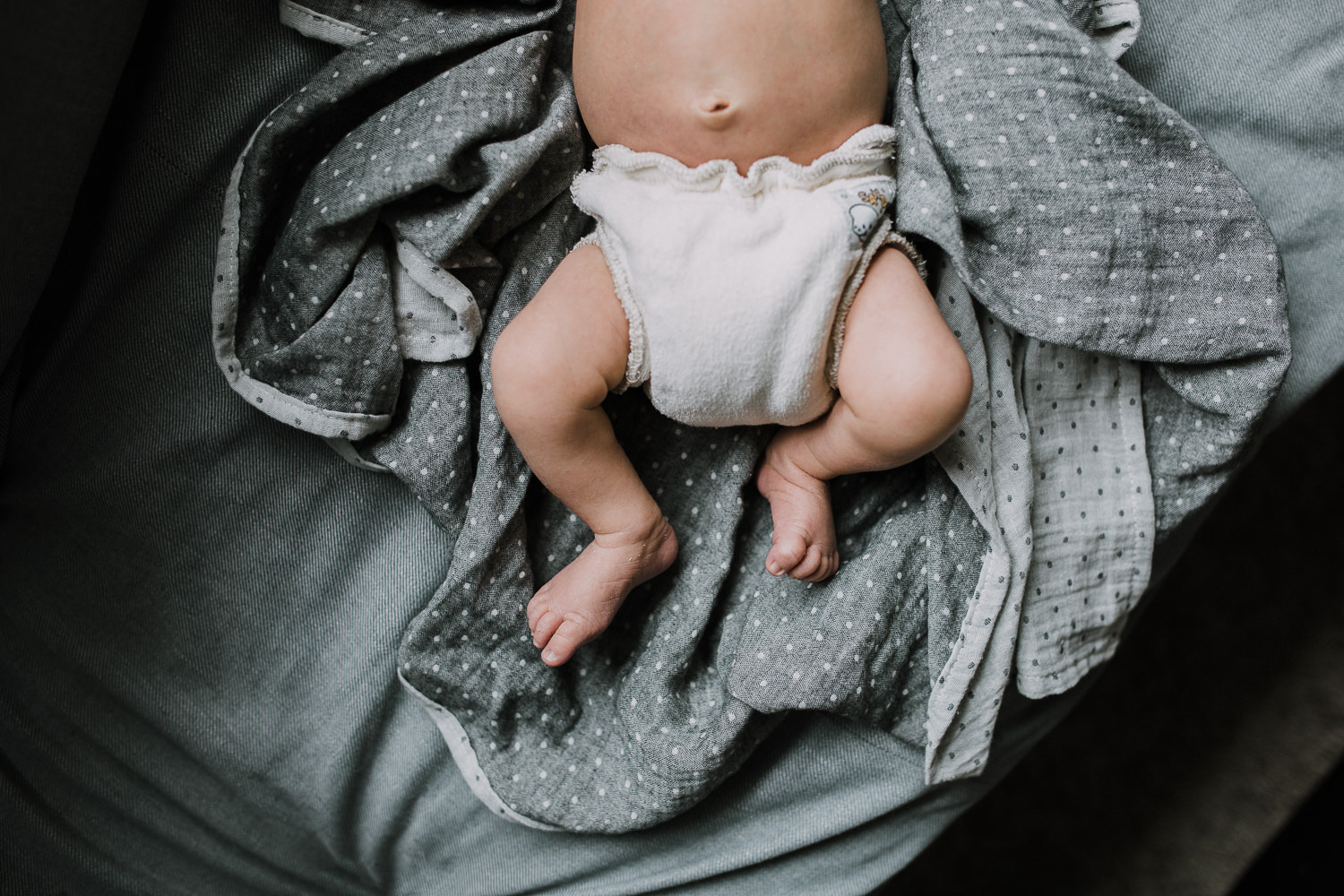 10 day old baby boy's feet in diaper on couch - Markham In-Home Family Photography