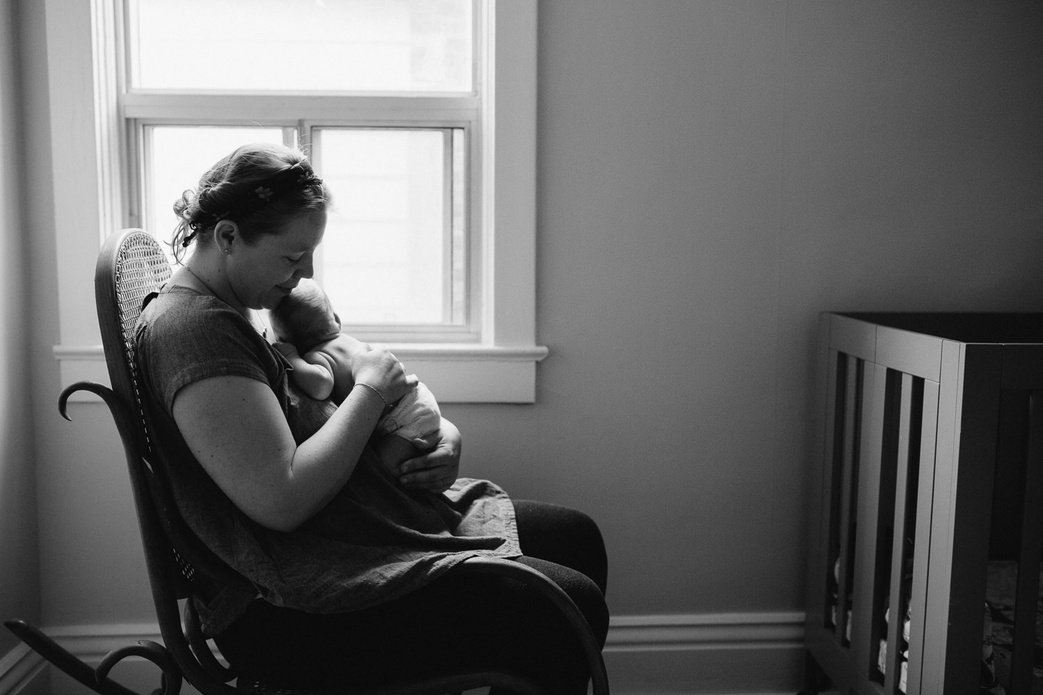 mom sitting in nursery rocker cuddling 10 day old baby boy on chest - Newmarket Lifestyle Family Photos