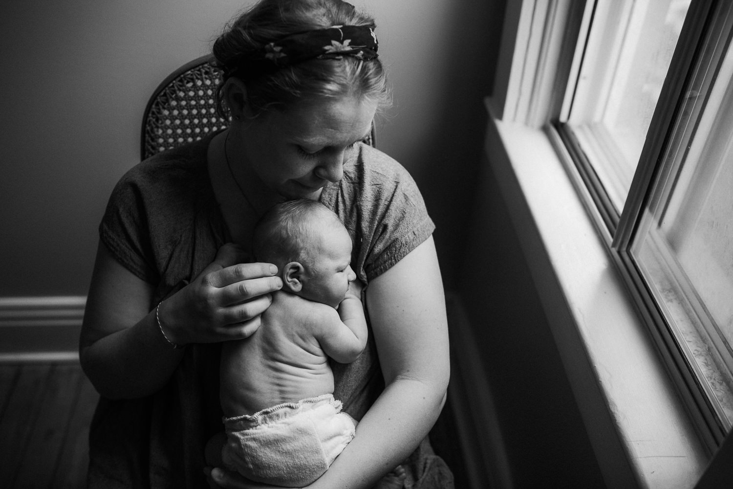 mom sitting in nursery rocker cuddling 10 day old baby boy on chest - Stouffville Lifestyle Family Photos