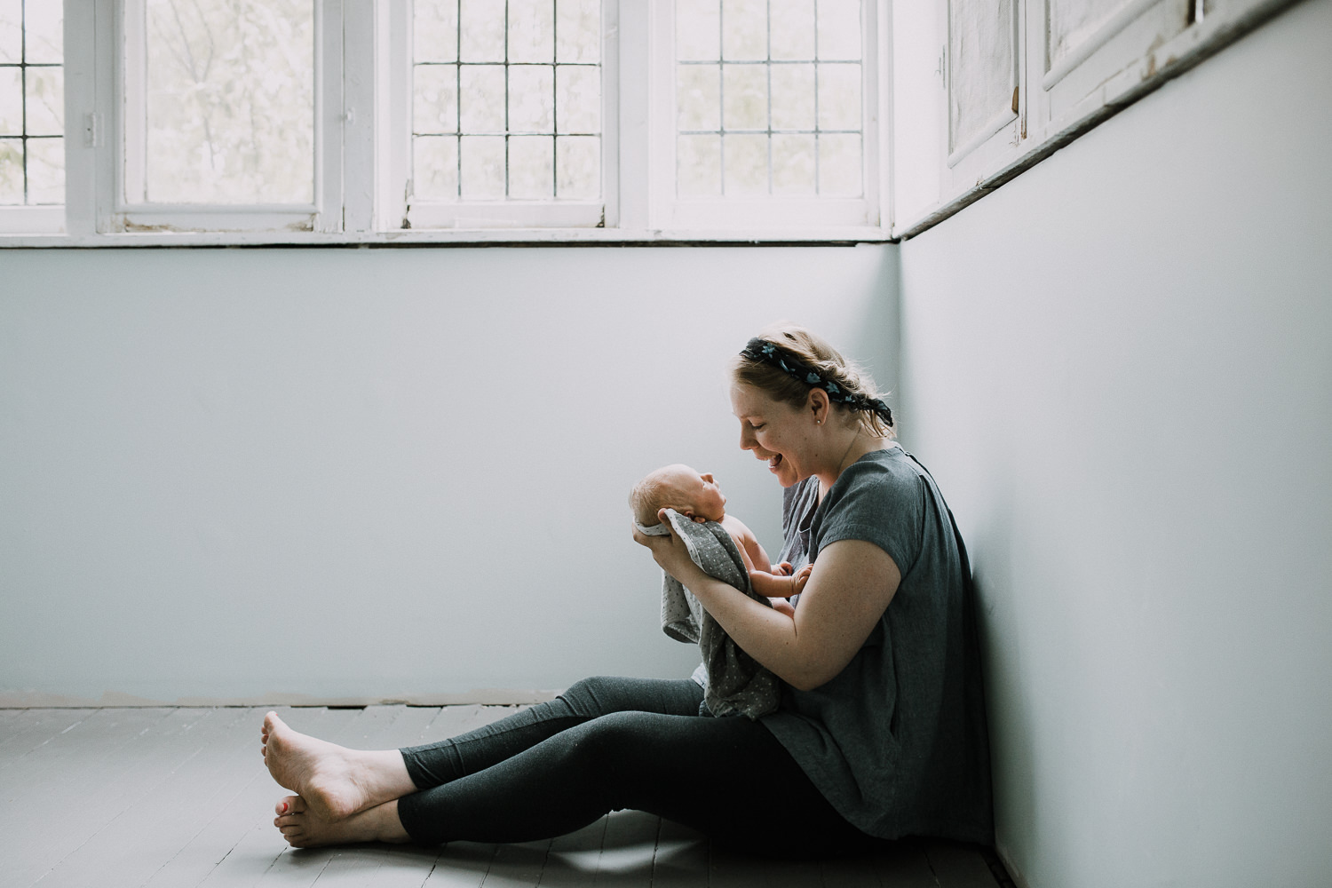 mom sitting on floor looking at 10 day old baby boy in her arms - Newmarket Lifestyle Family Photography
