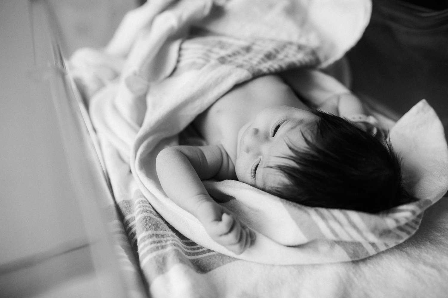 1 day old baby girl with lots of dark hair lying in hospital bassinet awake - Markham In-Hospital Photography 