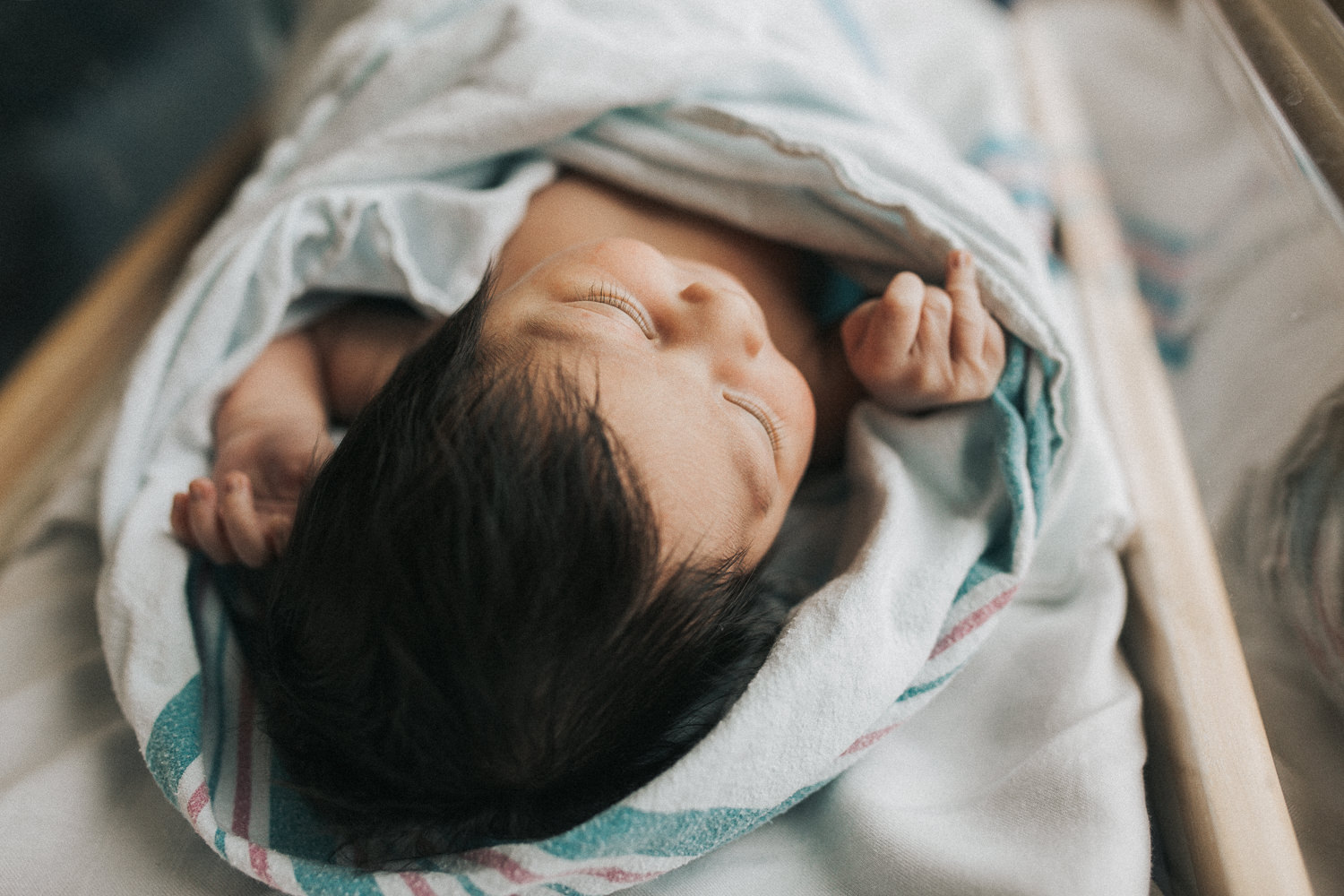 1 day old baby girl with lots of dark hair lying in hospital bassinet - Newmarket In-Hospital Photos