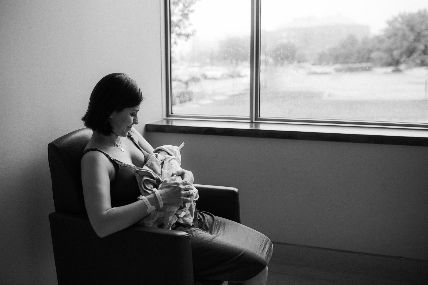 new mom sitting in chair holding 1 day old baby daughter - Barrie In-Hospital Photography