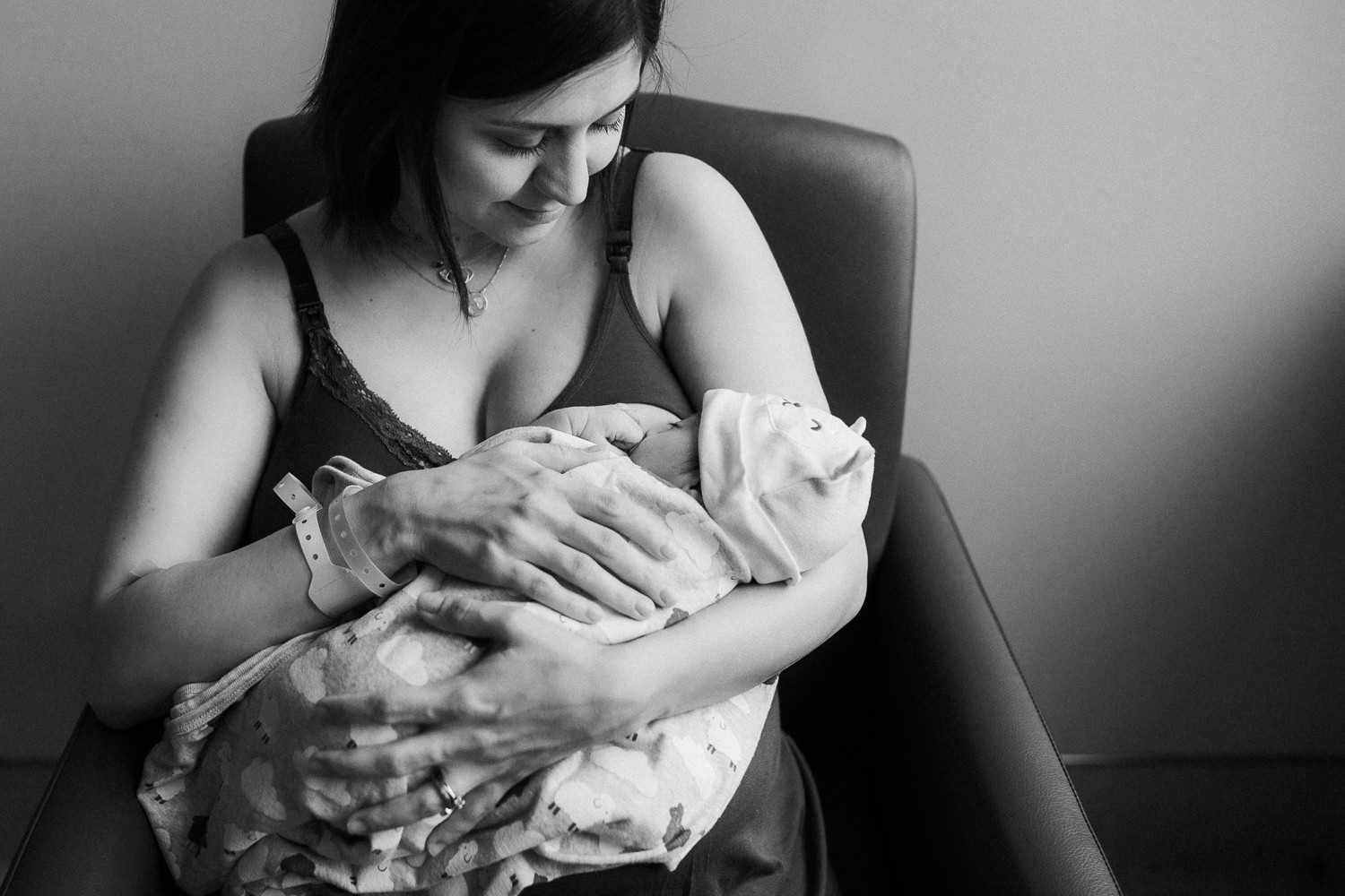 new mom sitting in chair holding 1 day old baby girl wrapped in swaddle - Stouffville Fresh 48 Photography