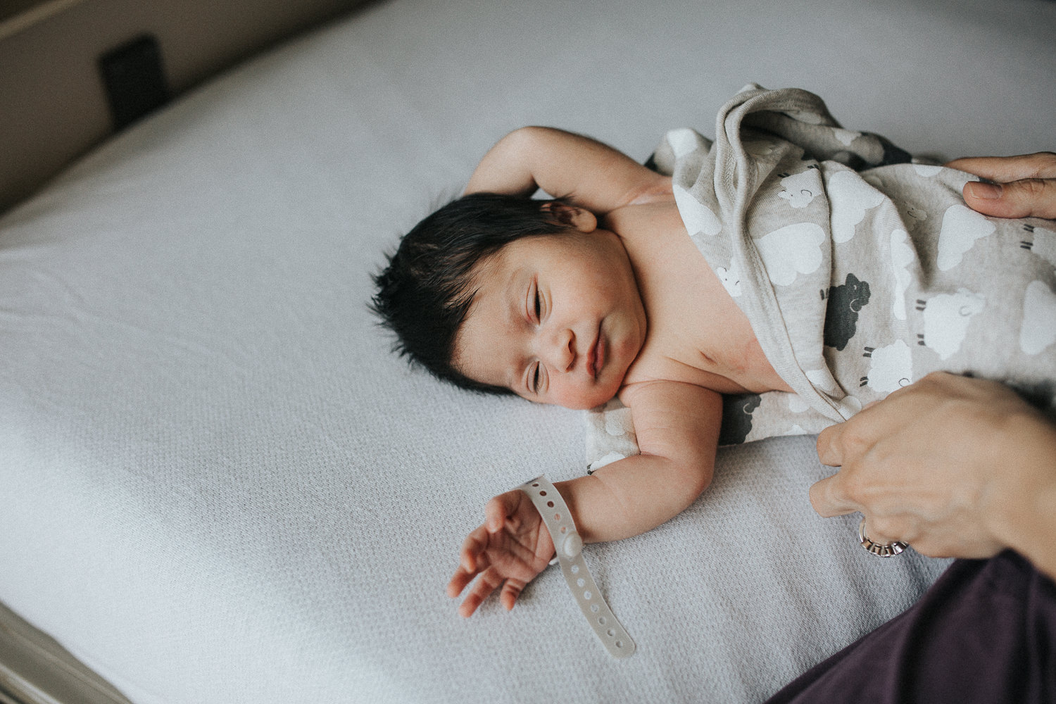1 day old baby girl with lots of dark hair in swaddle lying on hospital bed - Markham Fresh 48 Photography