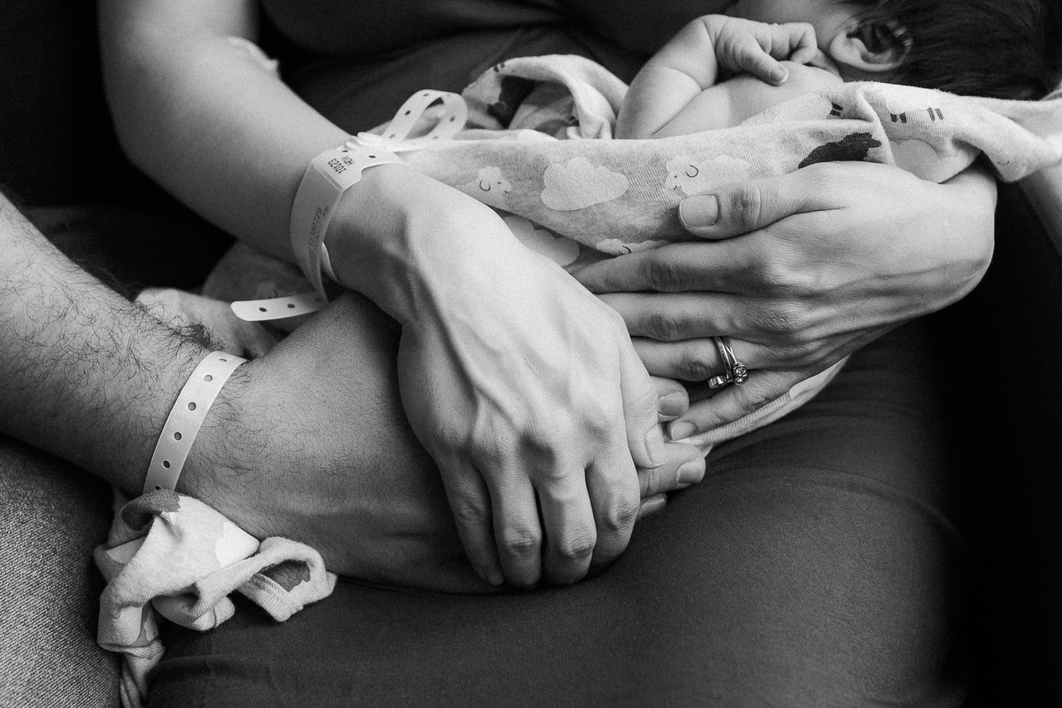 close up of new parent's hands with hospital bracelets as they hold their 1 day old baby girl - Markham Fresh 48 Photos