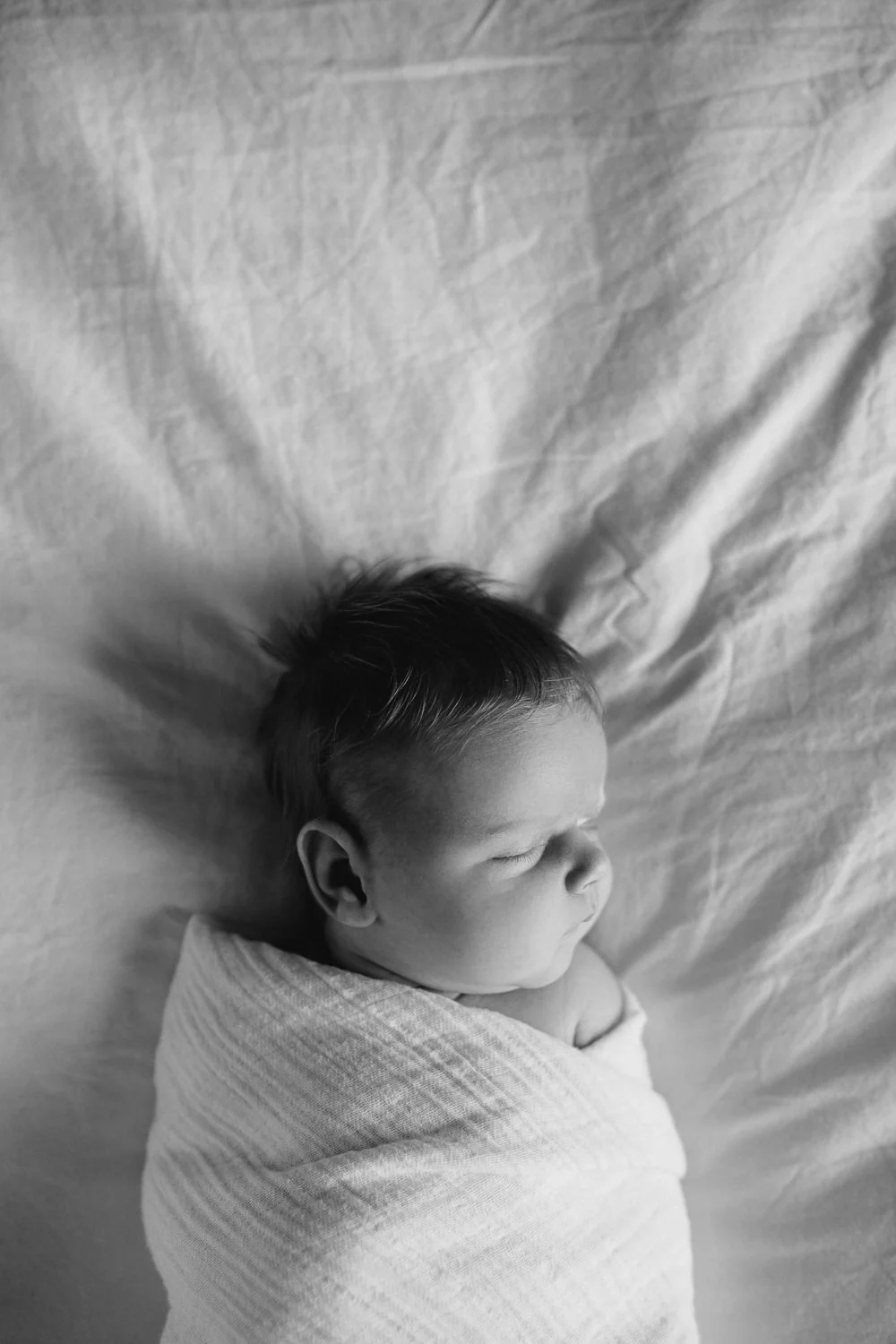 2 week old baby girl with red hair in white swaddle asleep on bed - Barrie Lifestyle Photography