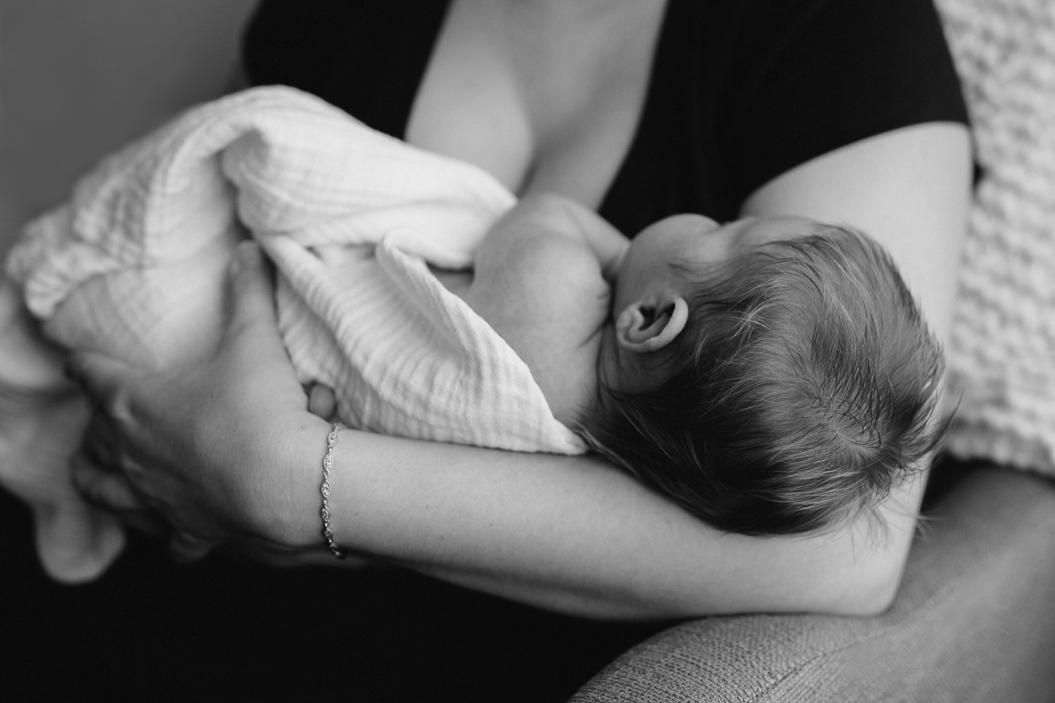 2 week old swaddled baby girl with lots of hair asleep in mother's arms - Newmarket In-Home Photos