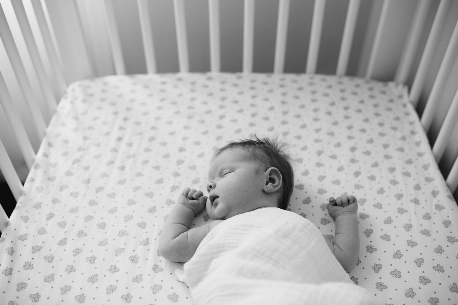 2 week old swaddled baby girl with red hair asleep in nursery crib - Markham In-Home Photos