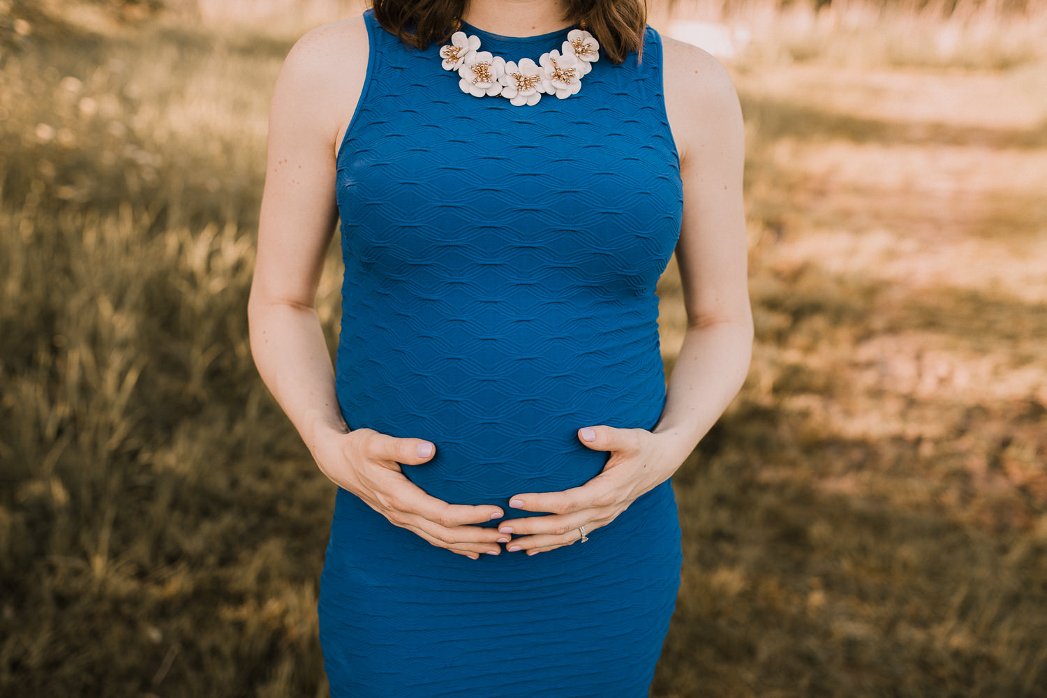 pregnant mom-to-be in blue dress holding baby bump at sunset -Newmarket Lifestyle Photos