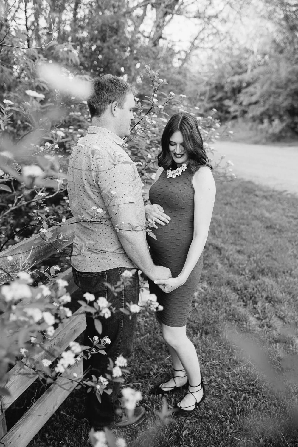 pregnant brunette mom-to-be in blue dress holding husband's hand and looking down at baby bump - Barrie Lifestyle Photography